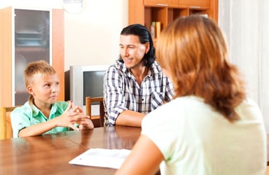 Woman Social Worker Sitting at a Table Talking to a Father and Son