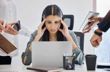 Stressed Out Woman at Laptop with People Around