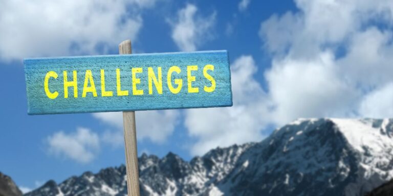 Blue Wood Sign with Yellow Challenges Text and Mountain in the Background