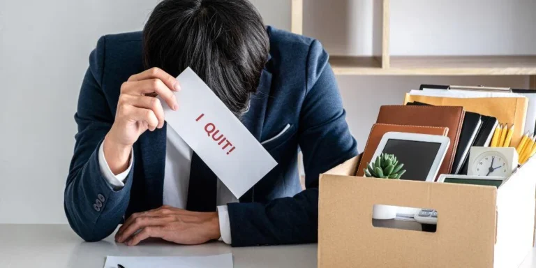 Burned Out Man at a Desk with Paper that Reads I Quit