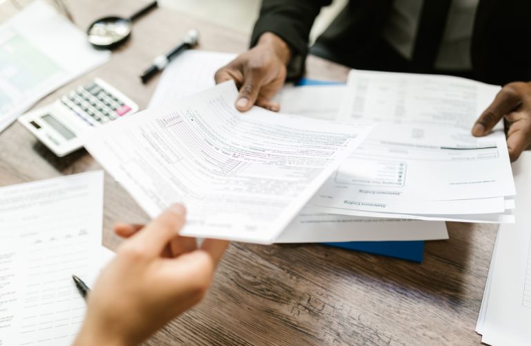 People Exchanging Paperwork at a Desk