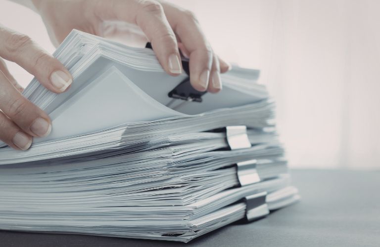 Person Going Through a Pile of Paperwork