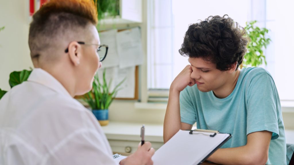 Social Worker Talking to Young Man and Taking Notes