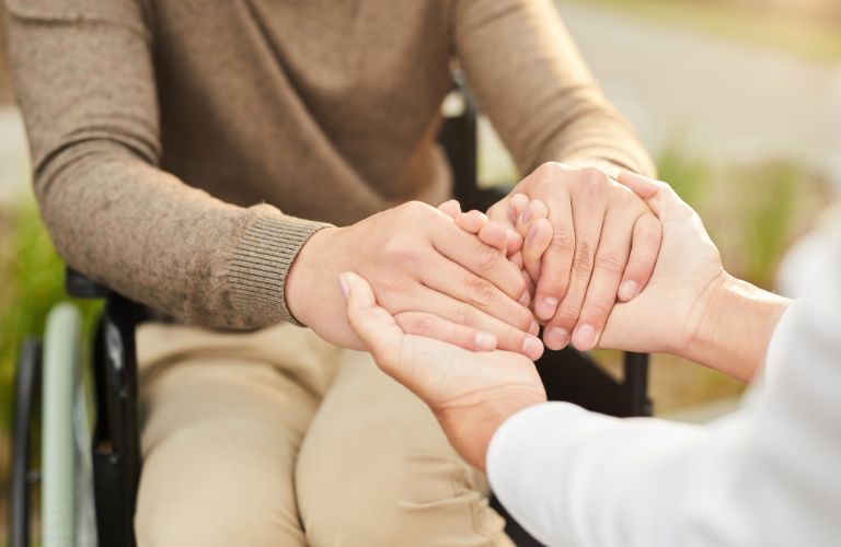 Social Worker Holding Hands of a Person in a Wheelchair