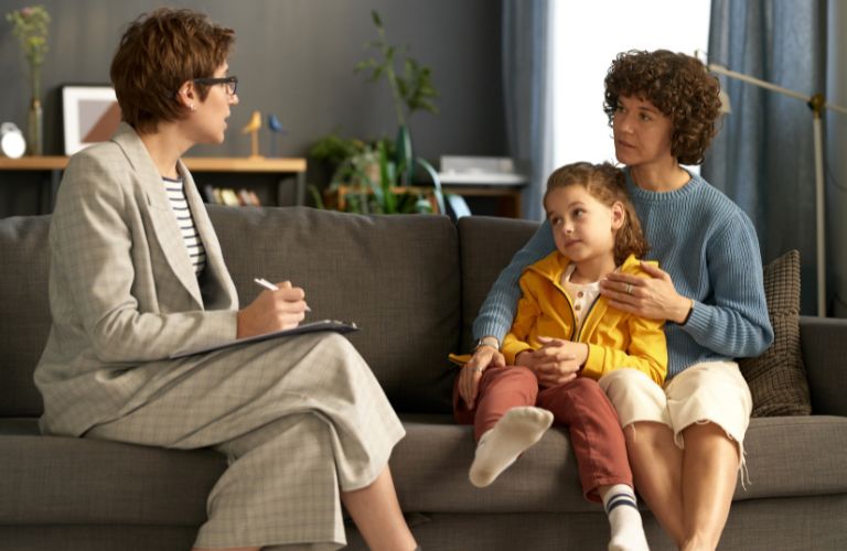 Female Social Worker Sitting on Couch with Mother and Daughter