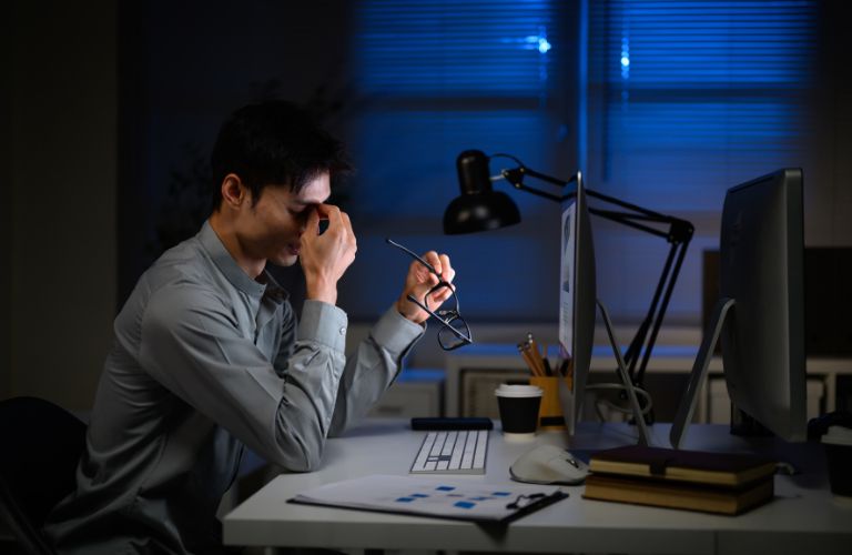 Stressed Out Social Worker Sitting at a Desk at Night