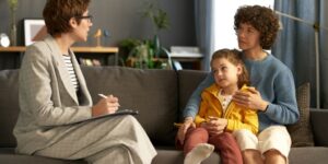 Woman Social Worker Sitting on a Couch Talking to Mother and Child